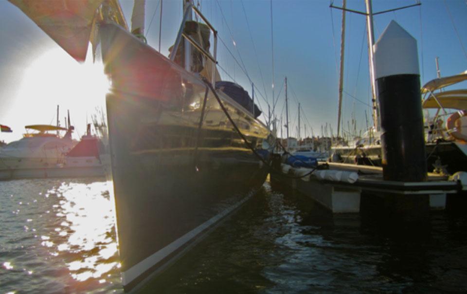 Sailing yacht Comar Comet 62 RS 2007 docked at marina, sun setting in background.