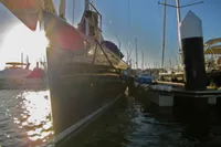 Sailing yacht Comar Comet 62 RS 2007 docked at marina, sun setting in background.