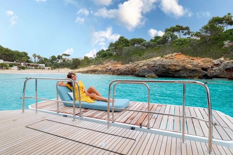  Yacht Photos Pics Woman relaxing on Lagoon 55 yacht deck, 2026 model, near scenic coastline.
