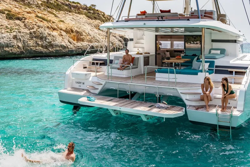  Yacht Photos Pics Luxurious 2026 Lagoon 55 yacht with people enjoying turquoise waters and sunbathing on deck.