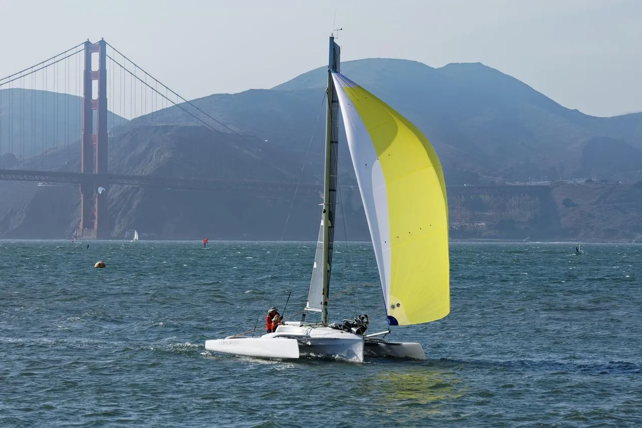 Sailboat Corsair 760 Dash 2018 with yellow sail near Golden Gate Bridge.