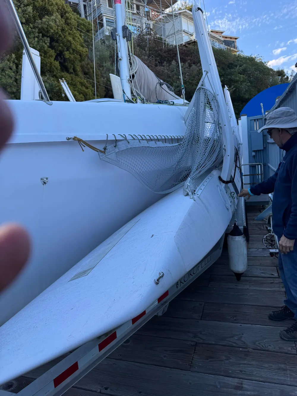 2018 Corsair 760 Sport sailboat on trailer, docked with a person nearby.