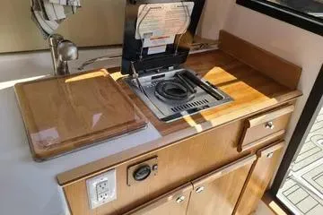  Yacht Photos Pics 2023 Cutwater C-248 Coupe kitchenette with stove, sink, and wooden cabinetry.