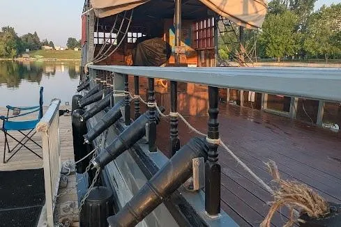  Yacht Photos Pics Custom 2016 pirate ship docked by a serene lake, featuring decorative cannons and wooden deck.