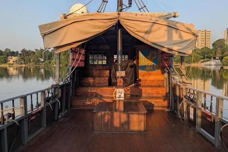  Yacht Photos Pics Custom 2016 pirate ship with wooden deck, docked by a serene lake, surrounded by greenery.