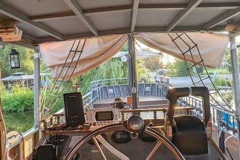  Yacht Photos Pics Steering wheel and controls of a 2016 custom pirate ship, docked near lush greenery.