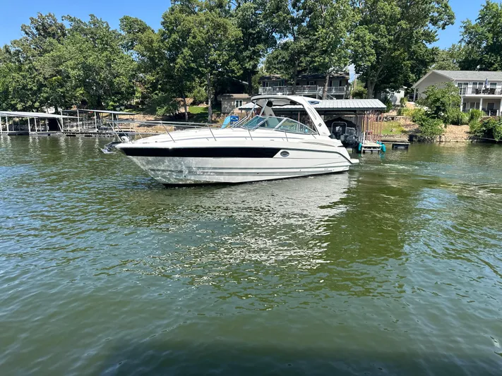  Yacht Photos Pics 2017 Monterey 355 Sport Yacht on a serene lake near a dock and trees.
