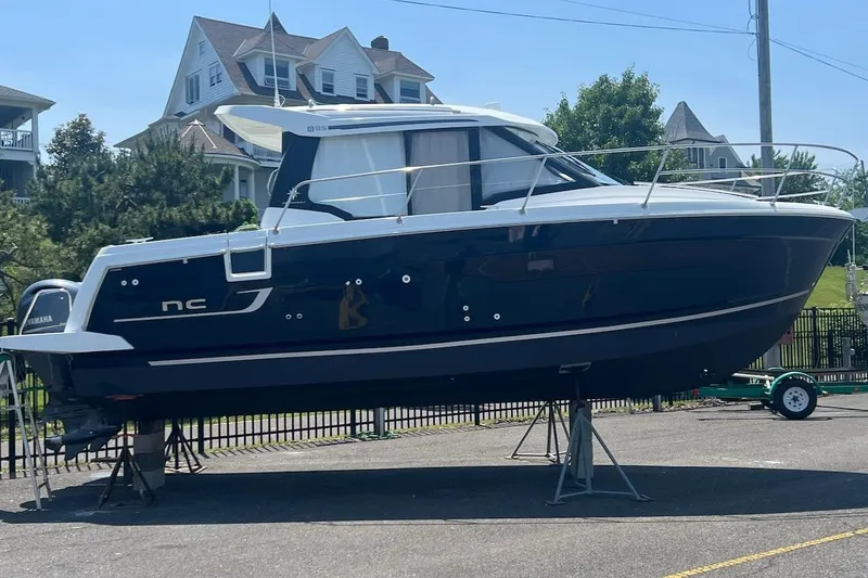Pisces Yacht Photos Pics 2021 Jeanneau NC 895 boat on stands, displayed outdoors near residential area.
