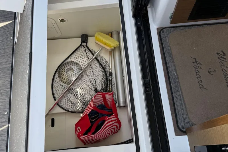 Pisces Yacht Photos Pics Storage compartment on a 2021 Jeanneau NC 895 boat with fishing net and cleaning tools.