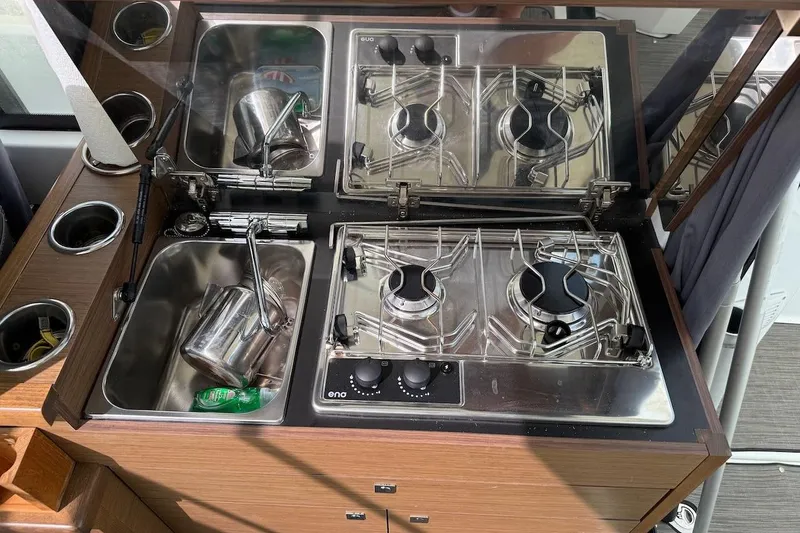 Pisces Yacht Photos Pics Compact kitchen area on a 2021 Jeanneau NC 895 boat, featuring a sink and dual-burner stove.
