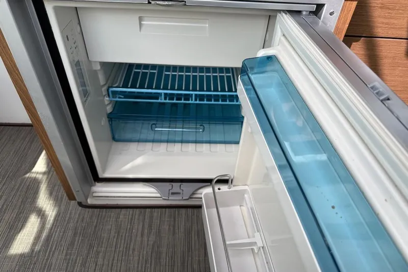 Pisces Yacht Photos Pics Open refrigerator inside 2021 Jeanneau NC 895 boat, featuring blue storage drawers.