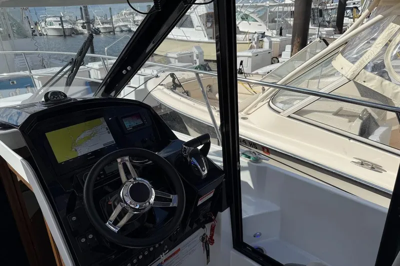 Pisces Yacht Photos Pics Interior view of 2021 Jeanneau NC 895 boat cockpit with steering wheel and navigation system.