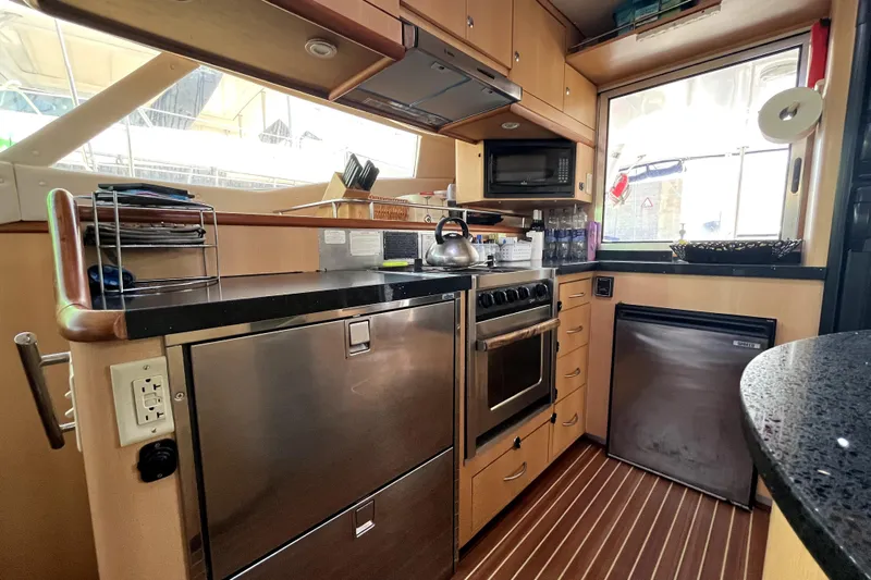  Yacht Photos Pics Compact kitchen in a 2009 Kelsall 58 KSS yacht with modern appliances and wood accents.