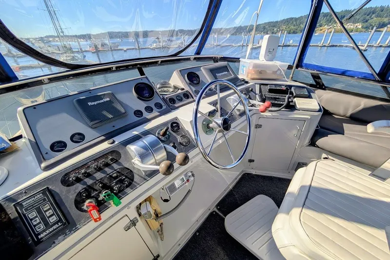 Gloryb2god Yacht Photos Pics 1990 Carver 55 yacht helm with navigation equipment, steering wheel, and marina view.