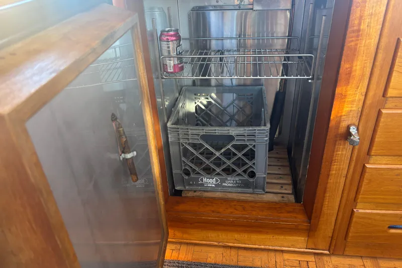 Maximon Yacht Photos Pics Open wooden cabinet on 1989 Grand Banks 46 Classic boat, showing storage with crate and soda can.