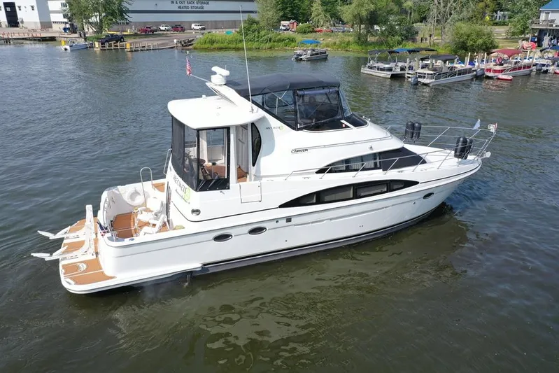  Yacht Photos Pics 2003 Carver 444 Cockpit Motor Yacht on calm water, dock and boats in background.