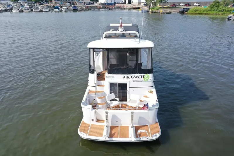  Yacht Photos Pics 2003 Carver 444 Cockpit Motor Yacht on calm water, rear view with docked boats in background.