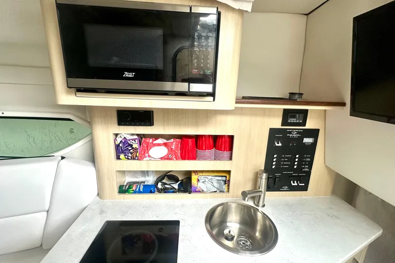  Yacht Photos Pics 2025 Regal 26 XO boat kitchenette with microwave, sink, and storage shelves.