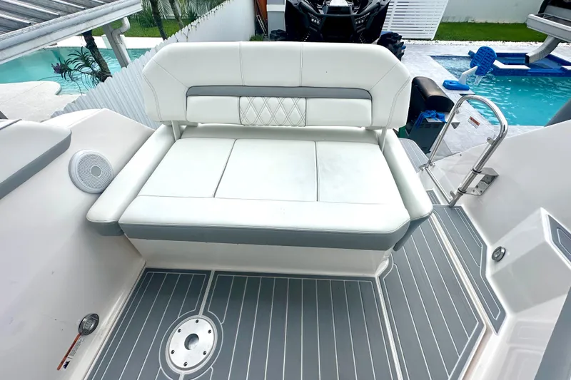  Yacht Photos Pics 2025 Regal 26 XO boat with white cushioned seating and gray deck near a pool.