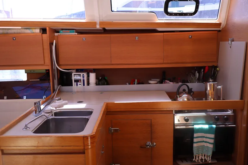  Yacht Photos Pics Interior of 2016 Dufour 382 Grand Large yacht kitchen with sink, stove, and wooden cabinets.