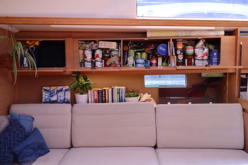  Yacht Photos Pics Interior of 2016 Dufour 382 Grand Large yacht with sofa, shelves, and stored provisions.