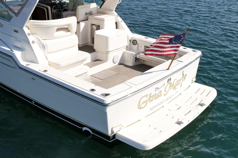 Gina Marie Yacht Photos Pics 1997 Tiara Yachts 3700 Open with American flag, docked in calm waters.