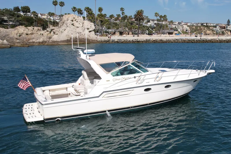 Gina Marie Yacht Photos Pics 1997 Tiara Yachts 3700 Open cruising near a rocky coastline with palm trees.