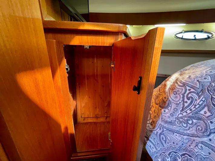 Gina Marie Yacht Photos Pics Wooden cabinet interior on 1997 Tiara Yachts 3700 Open, with open door and patterned bedding.