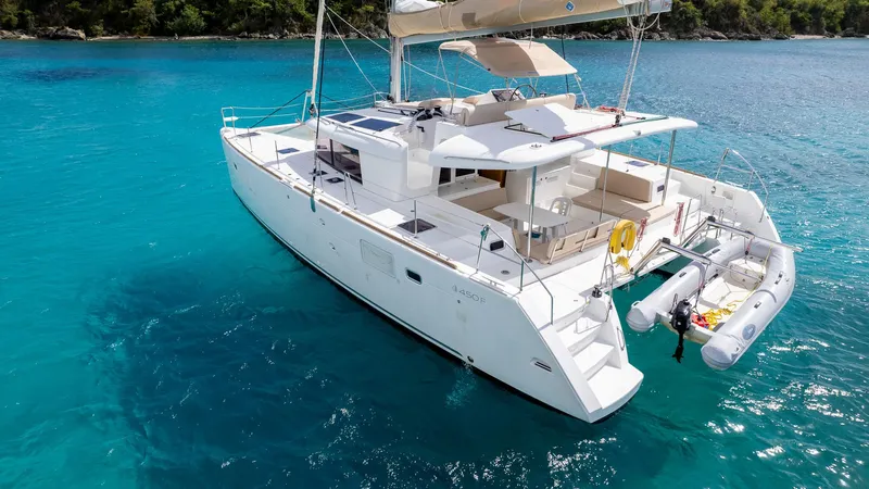 Altair Yacht Photos Pics 2018 Lagoon 450 F catamaran on clear blue water, featuring spacious deck and attached dinghy.