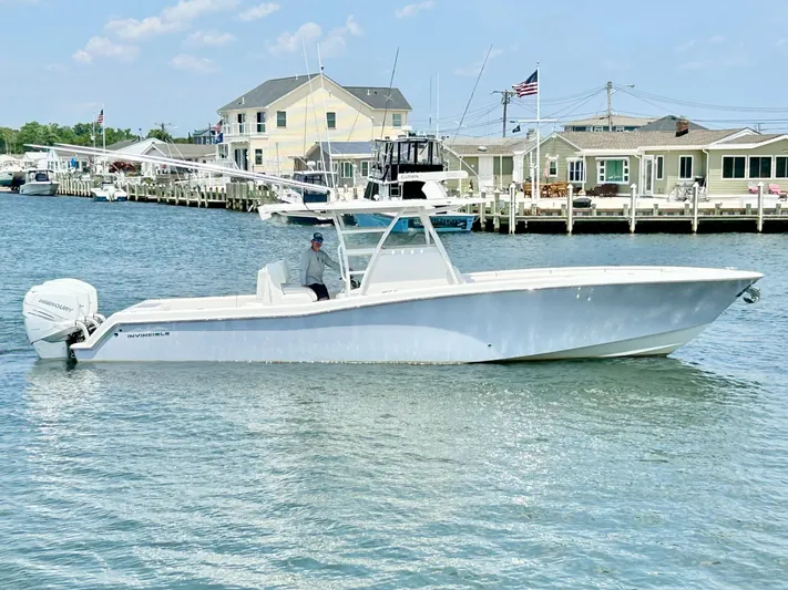  Yacht Photos Pics 2018 Invincible 36 Open boat cruising near a dockside community.