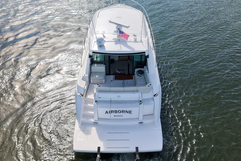  Yacht Photos Pics 2019 Tiara Yachts C49 Coupe cruising on water, rear view with American flag.