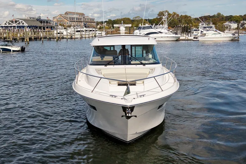  Yacht Photos Pics 2019 Tiara Yachts C49 Coupe in marina, surrounded by other boats and waterfront buildings.