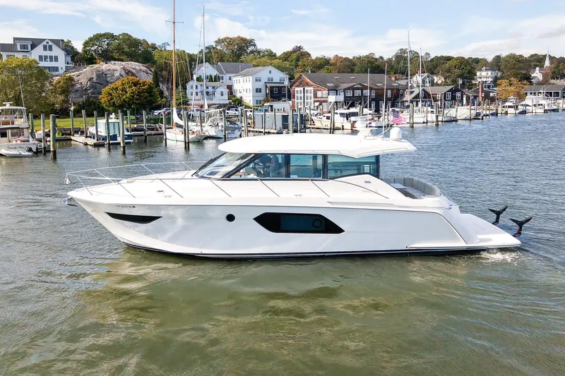  Yacht Photos Pics 2019 Tiara Yachts C49 Coupe cruising in a scenic marina setting.