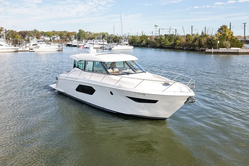  Yacht Photos Pics 2019 Tiara Yachts C49 Coupe cruising in a scenic marina setting.