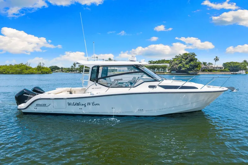  Yacht Photos Pics 2021 Boston Whaler 325 Conquest boat on calm water under a clear blue sky.