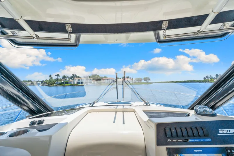  Yacht Photos Pics Cockpit view from a 2021 Boston Whaler 325 Conquest, overlooking a serene waterfront.