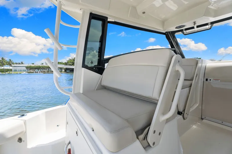  Yacht Photos Pics 2021 Boston Whaler 325 Conquest interior with seating, overlooking serene water and blue sky.