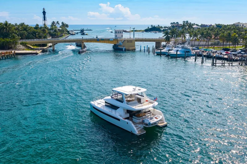 Better Now Yacht Photos Pics 2023 Leopard 46 Powercat cruising in a scenic coastal waterway near a lighthouse.