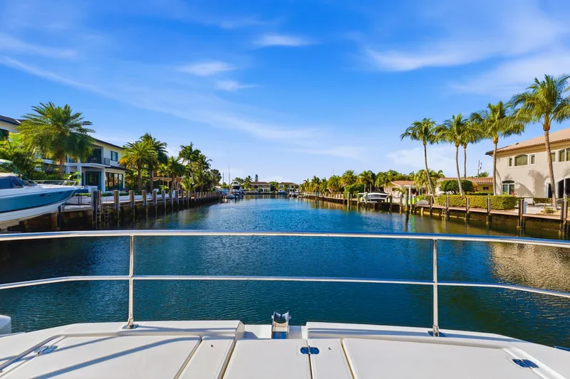 Better Now Yacht Photos Pics View from 2023 Leopard 46 Powercat, overlooking a serene canal with palm trees and houses.