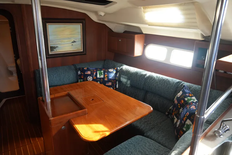 Andiamo Yacht Photos Pics Cozy interior of 1998 Hunter 410 sailboat with wooden table and cushioned seating.