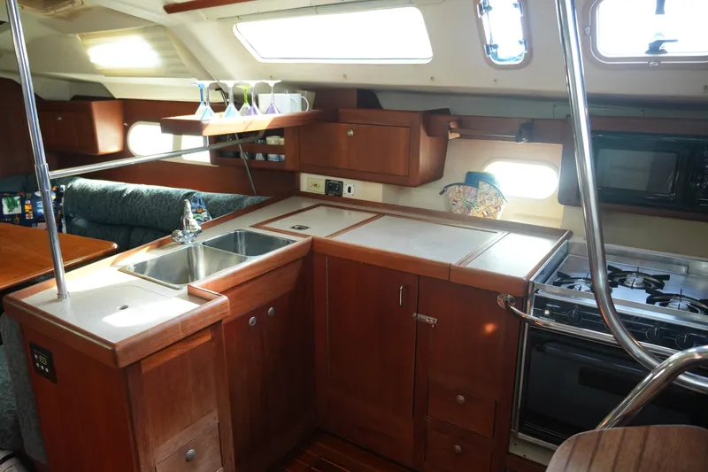 Andiamo Yacht Photos Pics Interior of 1998 Hunter 410 sailboat kitchen with wooden cabinets and stainless steel sink.