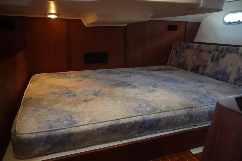 Andiamo Yacht Photos Pics 1998 Hunter 410 yacht interior cabin with a floral-patterned mattress and wooden paneling.