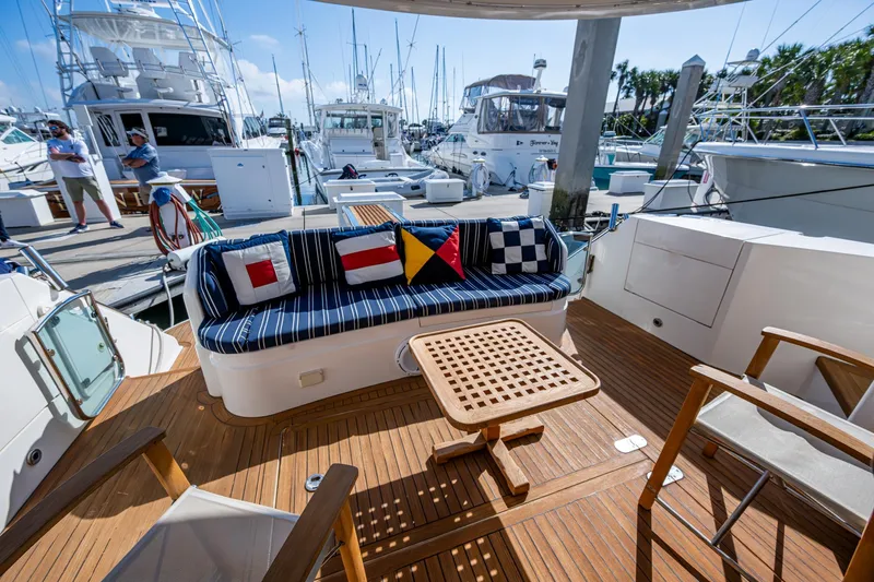 You Go Girl! Yacht Photos Pics Fairline Squadron 52 yacht deck with nautical-themed cushions, wooden table, and marina view.