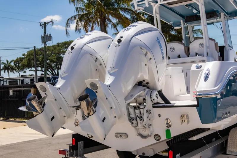  Yacht Photos Pics 2025 Edgewater 325CC boat with dual Yamaha outboard engines, parked near palm trees.