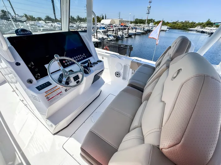 Yacht Photos Pics 2025 Edgewater 325CC boat cockpit with modern steering and plush seating at a marina.