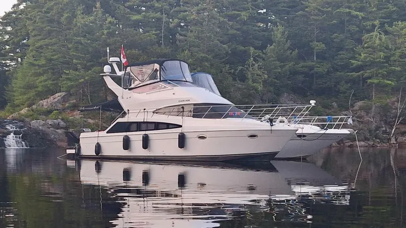  Yacht Photos Pics 2005 Carver 38 Super Sport yacht on calm water, surrounded by lush forest.
