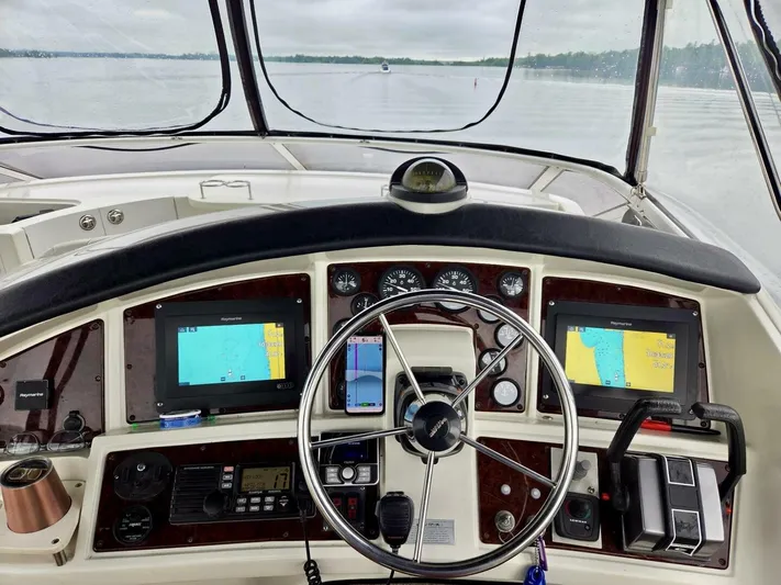  Yacht Photos Pics 2005 Carver 38 Super Sport helm with navigation screens and steering wheel on a calm lake.