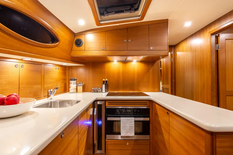 Independence Yacht Photos Pics Luxurious kitchen interior of 2021 Palm Beach Motor Yachts PB65, featuring sleek wood cabinetry.