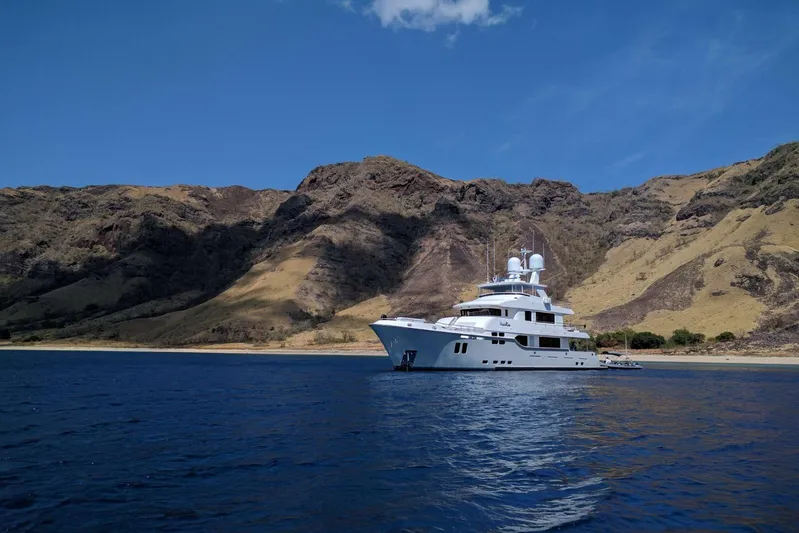  Yacht Photos Pics Luxurious 2017 Nordhavn 96 yacht anchored near scenic rocky coastline under clear blue sky.