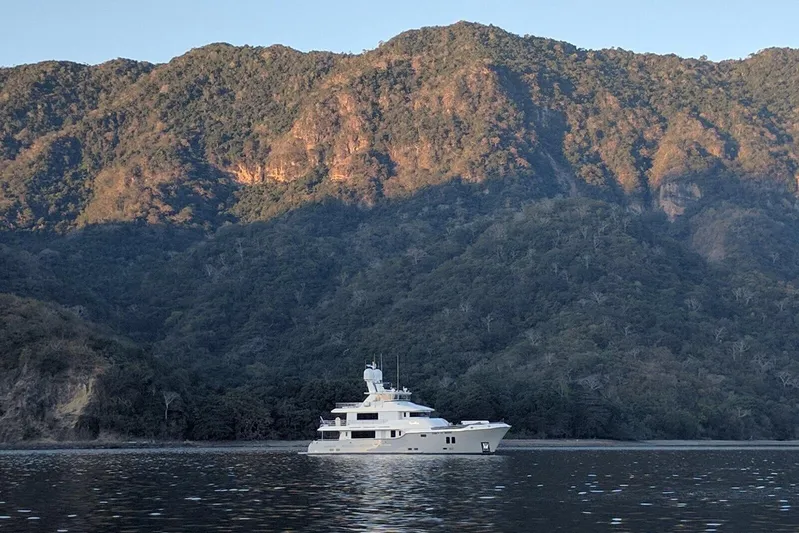  Yacht Photos Pics Luxurious 2017 Nordhavn 96 yacht cruising near lush, mountainous coastline.